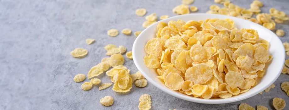 Corn flakes bowl sweeties with milk on gray cement background, close up, fresh and healthy breakfast design concept.