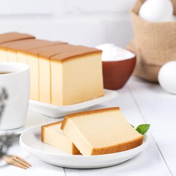 Castella (kasutera) - Beautiful delicious Japanese sliced sponge cake food on white plate over rustic white wooden table, close up, copy space design concept.