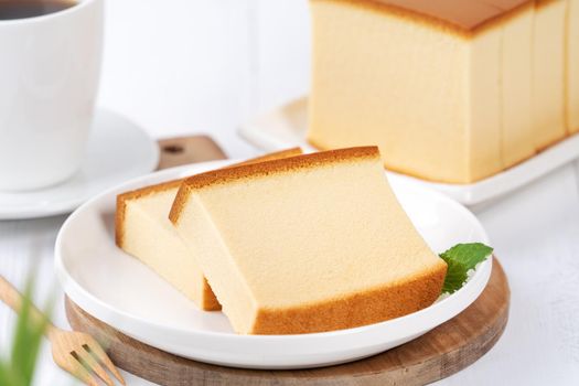 Castella (kasutera) - Beautiful delicious Japanese sliced sponge cake food on white plate over rustic white wooden table, close up, copy space design concept.