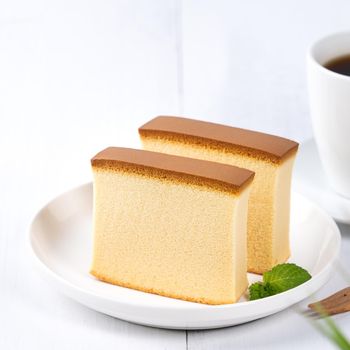 Castella (kasutera) - Beautiful delicious Japanese sliced sponge cake food on white plate over rustic white wooden table, close up, copy space design concept.