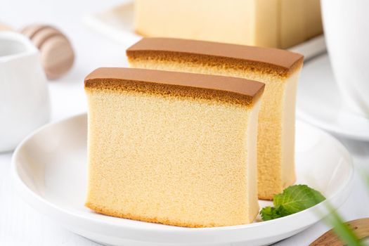 Castella (kasutera) - Beautiful delicious Japanese sliced sponge cake food on white plate over rustic white wooden table, close up, copy space design concept.