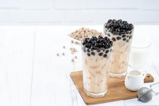 Bubble milk tea with tapioca pearl topping ingredient, famous Taiwanese drink on white wooden table background in drinking glass, close up, copy space