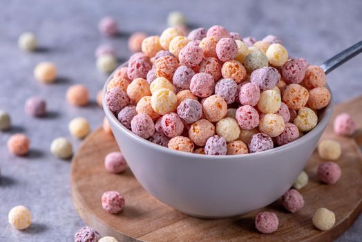 Colorful cereal corn balls mix, fruit flavor bowl sweets on gray cement background, close up, fresh, delicious and healthy breakfast, copy space design concept.