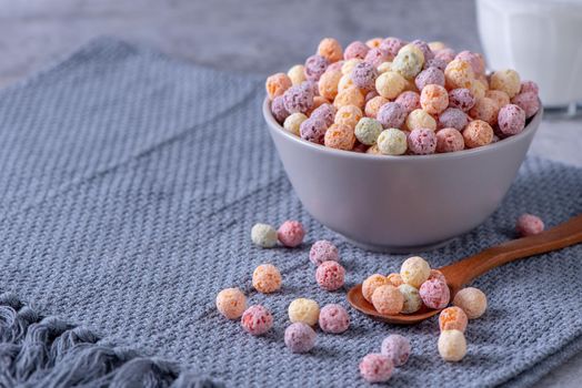 Colorful cereal corn balls mix, fruit flavor bowl sweets on gray cement background, close up, fresh, delicious and healthy breakfast, copy space design concept.