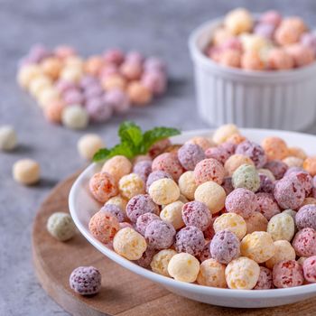 Colorful cereal corn balls mix, fruit flavor bowl sweets on gray cement background, close up, fresh, delicious and healthy breakfast, copy space design concept.