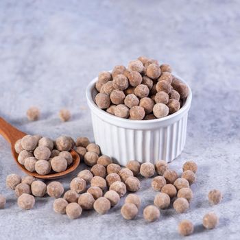Dry raw brown tapioca pearls isolated on gray cement concrete background, close up, ingredient of making bubble boba tapioca milk tea.