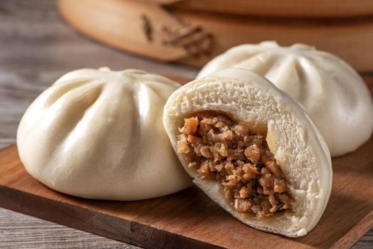 Delicious baozi, Chinese steamed meat bun is ready to eat on serving plate and steamer, close up, copy space product design concept.