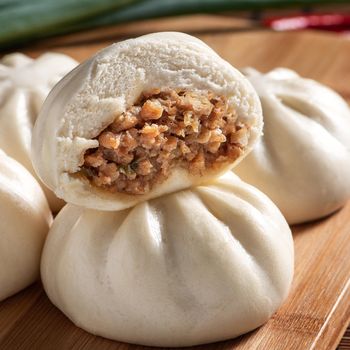 Delicious baozi, Chinese steamed meat bun is ready to eat on serving plate and steamer, close up, copy space product design concept.
