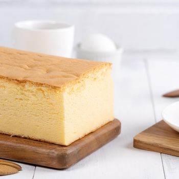Plain classic Taiwanese traditional sponge cake (Taiwanese castella kasutera) on a wooden tray background table with ingredients, close up.
