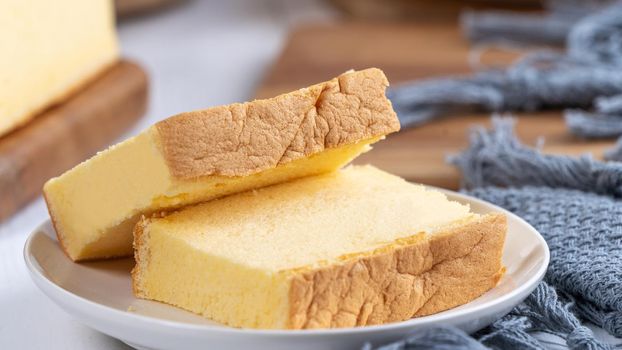 Plain classic Taiwanese traditional sponge cake (Taiwanese castella kasutera) on a wooden tray background table with ingredients, close up.