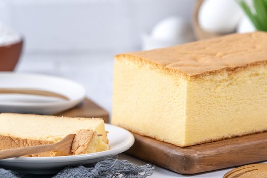 Plain classic Taiwanese traditional sponge cake (Taiwanese castella kasutera) on a wooden tray background table with ingredients, close up.
