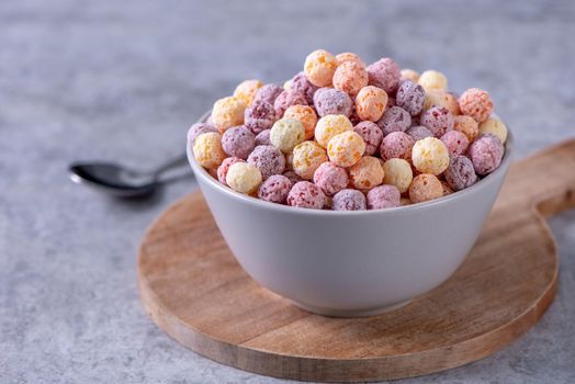 Colorful cereal corn balls mix, fruit flavor bowl sweets on gray cement background, close up, fresh, delicious and healthy breakfast, copy space design concept.