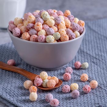 Colorful cereal corn balls mix, fruit flavor bowl sweets on gray cement background, close up, fresh, delicious and healthy breakfast, copy space design concept.
