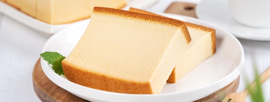 Castella (kasutera) - Beautiful delicious Japanese sliced sponge cake food on white plate over rustic white wooden table, close up, copy space design concept.