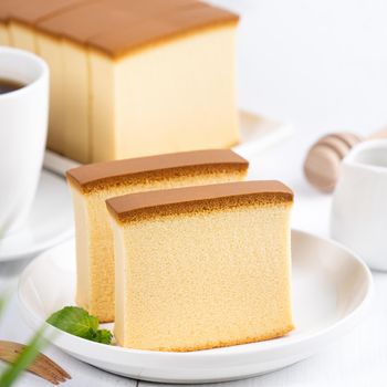 Castella (kasutera) - Beautiful delicious Japanese sliced sponge cake food on white plate over rustic white wooden table, close up, copy space design concept.