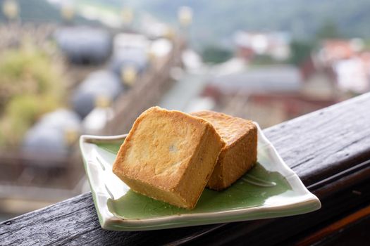 Delicious pineapple pastry in a plate for afternoon tea on wooden railing of a teahouse in Taiwan with beautiful landscape in background, close up.