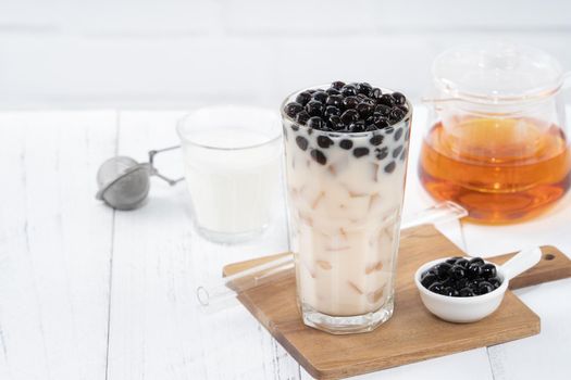 Bubble milk tea with tapioca pearl topping, famous Taiwanese drink on white wooden table background in drinking glass, close up, copy space