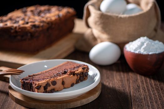 Chocolate flavor Taiwanese traditional sponge cake (Taiwanese castella kasutera) on a wooden tray background table with ingredients, close up.