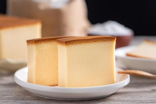 Castella (kasutera) - Delicious Japanese sliced sponge cake food on white plate over rustic wooden table, close up, healthy eating, copy space design.