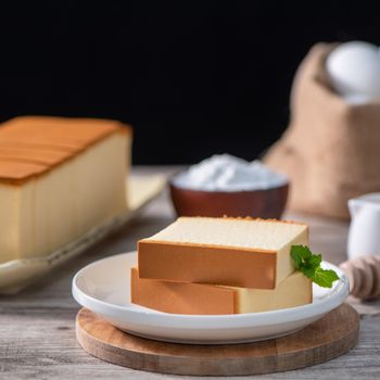 Castella (kasutera) - Delicious Japanese sliced sponge cake food on white plate over rustic wooden table, close up, healthy eating, copy space design.