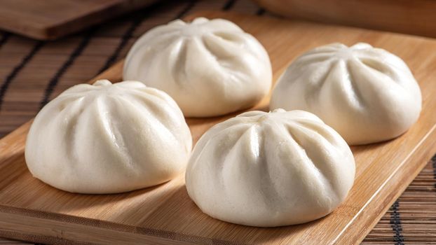 Delicious baozi, Chinese steamed meat bun is ready to eat on serving plate and steamer, close up, copy space product design concept.
