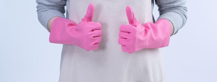 Young woman housekeeper in apron is wearing pink gloves to clean the table, concept of preventing virus infection, housekeeping service, close up.