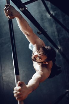 Strong young muscular man doing pull-up exercise at the gym. 