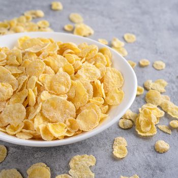 Corn flakes bowl sweeties with milk on gray cement background, close up, fresh and healthy breakbast design concept.