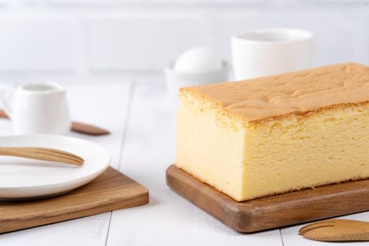 Plain classic Taiwanese traditional sponge cake (Taiwanese castella kasutera) on a wooden tray background table with ingredients, close up.