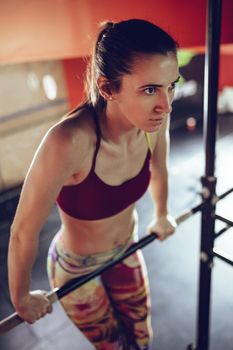 Beautiful young strong muscular woman doing pull-up exercise at the gym. 