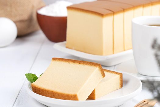 Castella (kasutera) - Beautiful delicious Japanese sliced sponge cake food on white plate over rustic white wooden table, close up, copy space design concept.