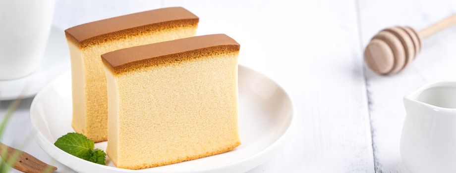 Castella (kasutera) - Beautiful delicious Japanese sliced sponge cake food on white plate over rustic white wooden table, close up, copy space design concept.