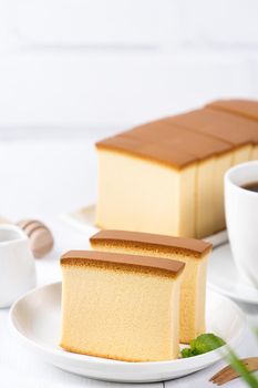 Castella (kasutera) - Beautiful delicious Japanese sliced sponge cake food on white plate over rustic white wooden table, close up, copy space design concept.