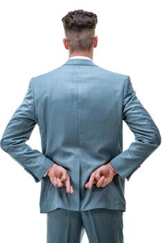Rear view of a handsome man holding his fingers crossed behind his back, hoping for a positive outcome, isolated on white background.