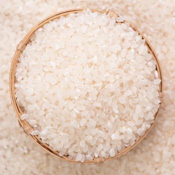 Raw rice in a bowl and full frame in the white background table, top view overhead shot, close up