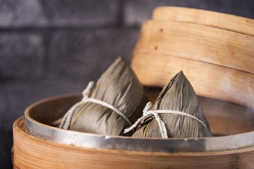 Rice dumpling, zongzi - Chinese rice dumpling zongzi on black brick background slate table, concept of Dragon Boat Festival traditional food, close up.