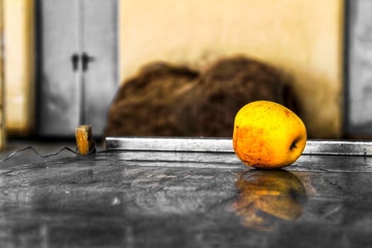 Abandoned yellow apple over metal surface on the street in Spain