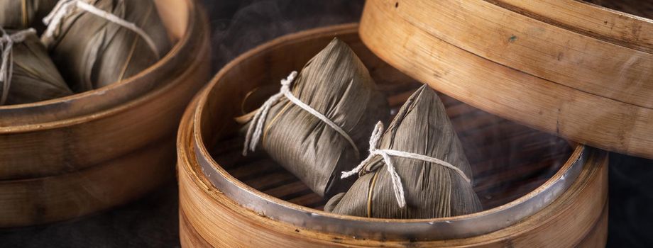 Rice dumpling, zongzi - Chinese rice dumpling zongzi on black brick background slate table, concept of Dragon Boat Festival traditional food, close up.