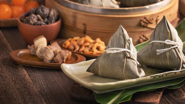 Rice dumpling - Chinese zongzi food in a steamer on wooden table with red brick wall, window background at home for Dragon Boat Festival concept, close up.