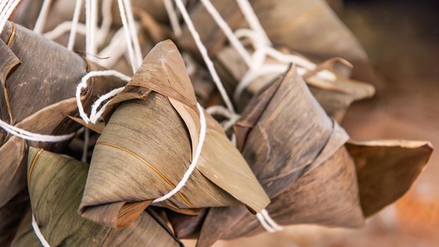 Rice dumpling - Chinese zongzi food in a steamer on wooden table with red brick wall, window background at home for Dragon Boat Festival concept, close up.
