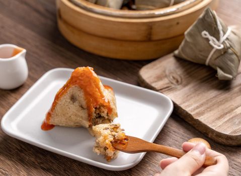 Eating zongzi - Dragon Boat Festival Rice dumpling young Asian woman eating Chinese traditional food on wooden table at home celebration, close up