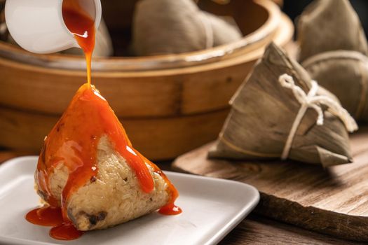 Eating zongzi - Dragon Boat Festival Rice dumpling young Asian woman eating Chinese traditional food on wooden table at home celebration, close up