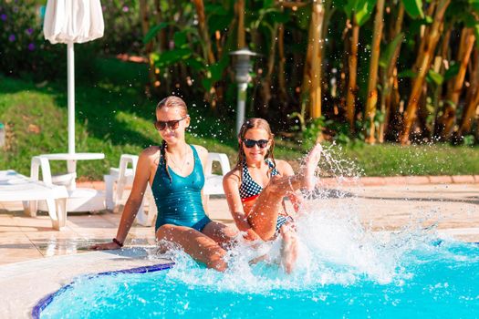 Happy beautiful girls having fun at the pool at the resort