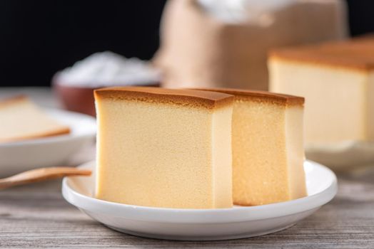 Castella - Delicious Japanese sliced sponge cake food on white plate over rustic wooden table, close up, healthy eating, copy space design.