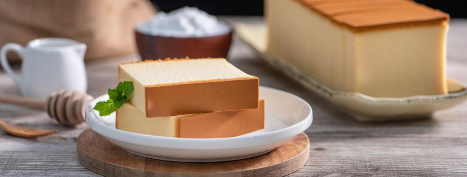 Castella - Delicious Japanese sliced sponge cake food on white plate over rustic wooden table, close up, healthy eating, copy space design.