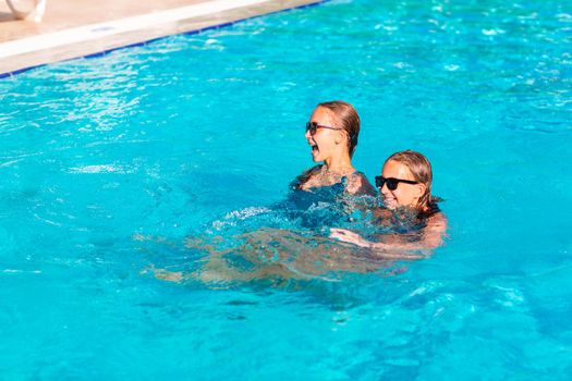 Happy beautiful girls having fun at the pool at the resort