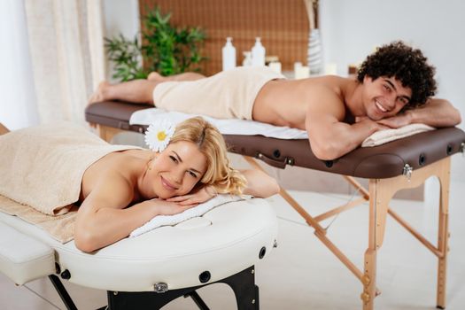 Young satisfied woman and man enjoying at the beauty salon, lying down and waiting for relaxing  massage. 