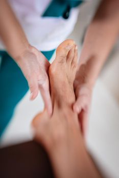 Close-up of a hads of female therapist massaging young man's foot at beauty salon. Selective focus.