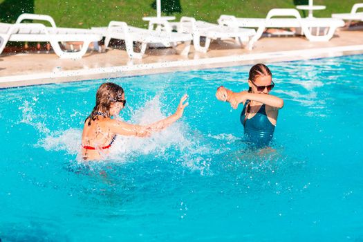 Happy beautiful girls having fun at the pool at the resort