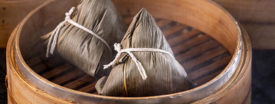 Rice dumpling, zongzi - Chinese rice dumpling zongzi on black brick background slate table, concept of Dragon Boat Festival traditional food, close up.